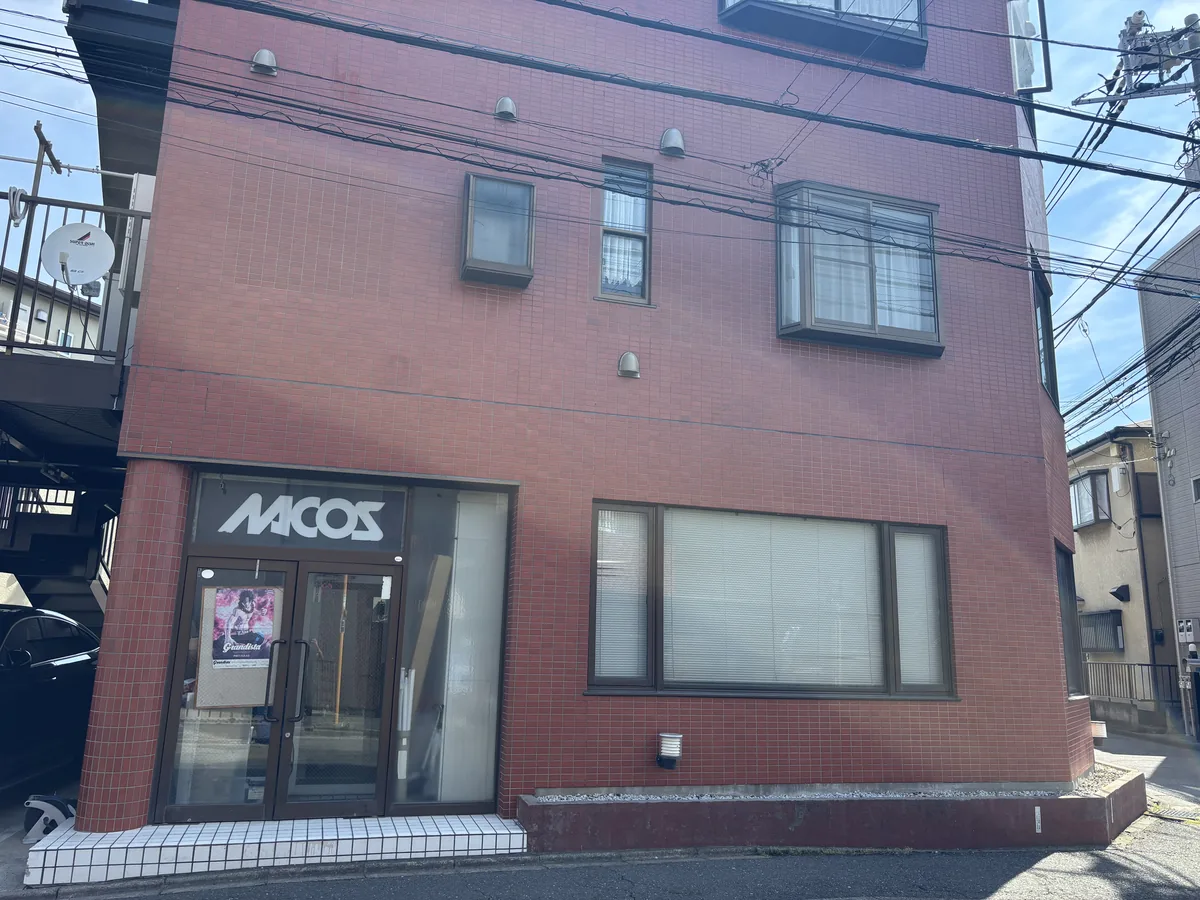 株式会社ナコス本社の外観。赤いタイル張りの建物にNACOSの看板