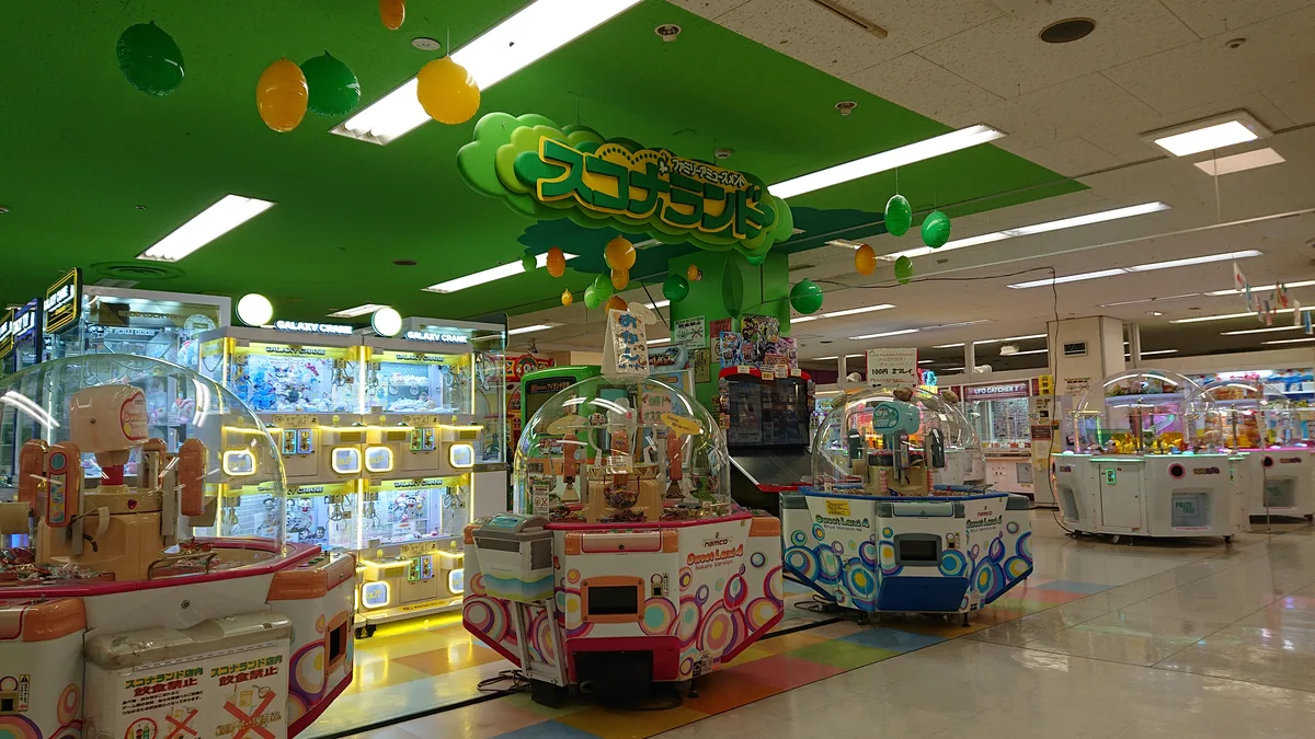 スコナランド金沢シーサイド店の店内全景。緑の木の装飾の下にゲーム機が並ぶ